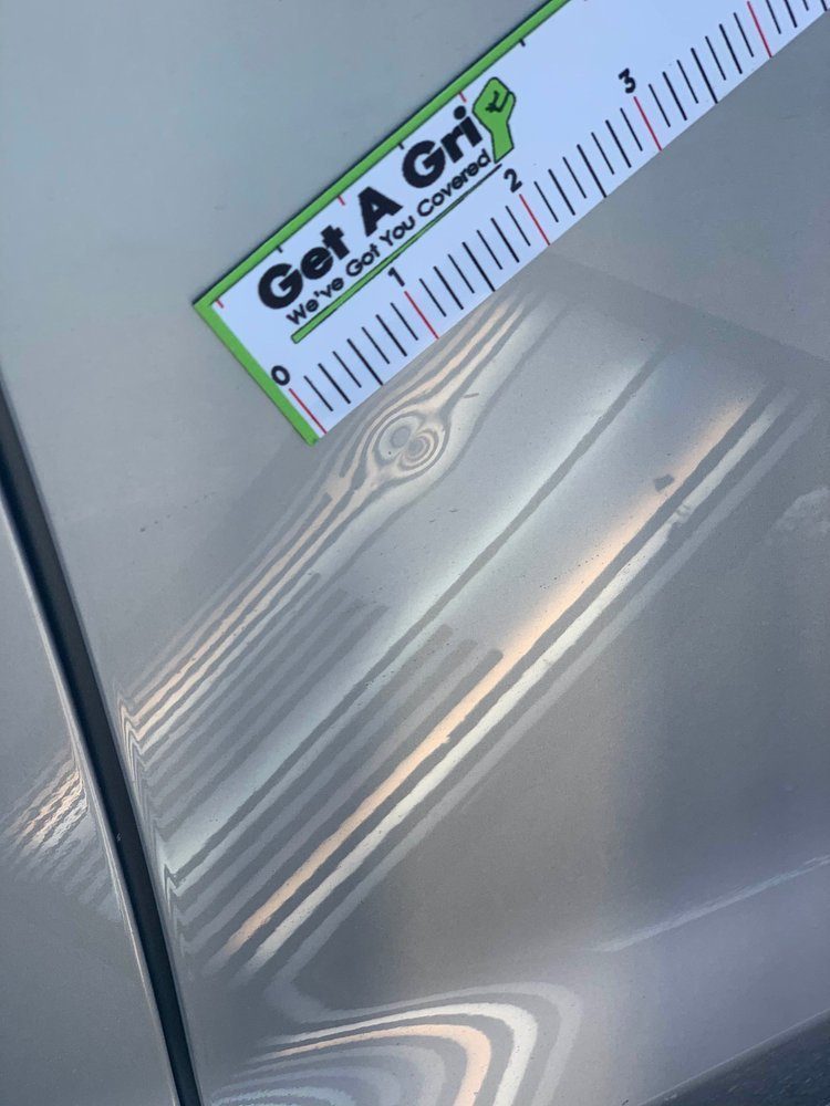 A technician measuring a dent on an automotive panel
